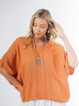 Remerón tipo poncho color naranja confeccionado en lino italiano, con escote en V y bolsillos laterales.