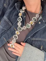Collar plateado tipo corbatín con piedras de colores.