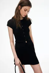 Saco corto negro en punto acanalado fino de mezcla de viscosa. Modelo entallado de manga corta con cuello redondo y cierre de botones.