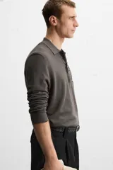 Polo de hombre color gris oscuro, de punto ligero tejido en hilatura con mezcla de seda y algodón. Tiene cuello solapa con cierre frontal de botonadura, manga larga y acabados en rib.