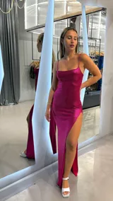 Vestido largo fucsia con breteles finos y abertura lateral en la pierna.