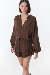 Camisa beige de manga larga con botones y detalles de encaje.