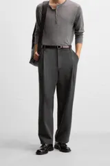 Pantalón relaxed fit color verde oscuro, con pliegues en la parte delantera, bolsillos laterales y traseros de ojal. Cierre frontal con cremallera y botón.