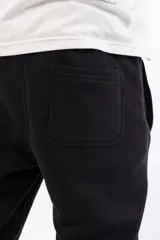 Pantalón de jogging negro de corte holgado con logo 'VERNAL' bordado en azul en el muslo izquierdo.