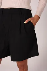 Bermuda color crema de lino con tiro alto, elástico en la parte trasera de la cintura, bolsillos delanteros y cierre frontal con cremallera y botón.