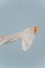 Camisa celeste de algodón con cuello alto y volados frontales. Mangas largas con puños fruncidos.