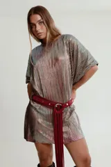 Cinturón de cuero color bordó con hebilla circular plateada y flecos largos.