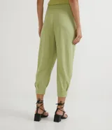 Pantalón jogger verde claro de tejido Orly (malla), con cintura elastizada, pliegues y amarre frontal con cuentas de madera.