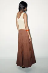 Falda larga color marrón chocolate, de tiro medio con cintura elástica ajustable con lazada y bajo acabado en paneles.