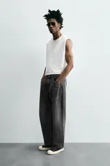 Pantalón de jean gris oscuro, corte amplio, con cinco bolsillos, efecto lavado y cierre frontal con cremallera y botón.