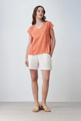 Remera color durazno con escote en V y detalle de vainillas en los laterales. De manga corta y corte recto.