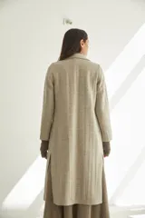 Tapado largo con cuello solapa y corte recto, color gris claro. Tiene cierre frontal con botones ocultos, tajos laterales y bolsillos escondidos en el corte lateral. Está forrado y confeccionado en lana fina sin teñir, diseñada exclusivamente por Don Baez. Hecho 100% en Uruguay.