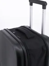 Valija rígida de viaje color negro con diseño de líneas verticales en la parte inferior y cuatro ruedas dobles.