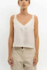 Top sin mangas color beige claro, con escote en V pronunciado y breteles finos. Presenta un calce recto y holgado.