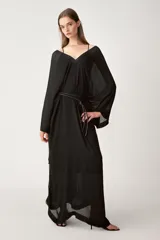 Vestido tipo capa color negro confeccionado en hilatura de viscosa, con escote pico, manga corta y bajo asimétrico desflecado.