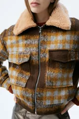 Campera a cuadros marrón y azul con cuello de piel sintética y cierre frontal.