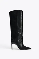 Bota alta de cuero sintético negro con detalles de pespuntes en contraste y puntera de gamuza. Tiene taco fino y tiradores laterales.
