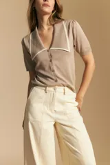 Pantalón ancho de tiro alto, color negro, con costuras contrastantes en blanco que definen los bolsillos y los bordes.