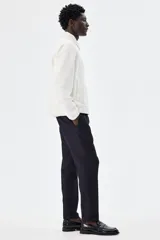 Pantalón tobillero azul marino de sarga suave con cintura elástica y cordón ajustable. Tiene bolsillos laterales y traseros ribeteados, piernas con pliegues cosidos y doblez en el bajo.