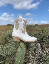 Botas cortas negras de cuero con bordados blancos estilo cowboy.