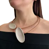 Collar corto de cuero marrón con dos óvalos de cuero color plateado.
