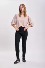 Pantalón de jean skinny negro, tiro alto, corte ajustado y largo al tobillo.