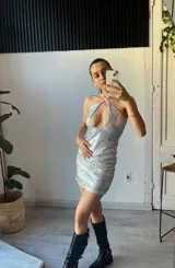 Minivestido negro de lentejuelas con cuello halter y abertura en el pecho.