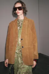 Blazer de cuero color marrón, con cuello solapa de muescas y manga larga. Bolsillos delanteros ocultos en costura y cierre frontal con botones.