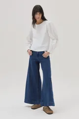 Blusa blanca de mangas largas abullonadas con puños elásticos y lazos.
