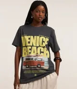 Remera gris con estampa de la frase "Venice Beach" en amarillo y una imagen de una camioneta con tablas de surf.