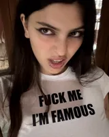 Baby tee de jersey blanco con estampado gráfico en negro que dice 'FUCK ME I’M FAMOUS'.