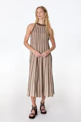 Vestido largo de tejido de punto, color celeste con rayas verticales en azul oscuro y brillo sutil por el lurex. Diseño sin mangas con cuello halter y silueta en A.