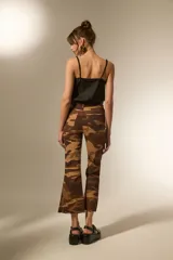 Pantalón de jean estampado camuflado en tonos marrones y beige, de corte flare, calce alto y ruedo deshilachado.