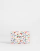 Billetera rectangular de cuerina con estampado floral multicolor. Tiene solapa con broche para cerrar y tag metálico con logo.