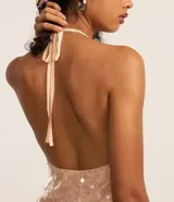 Blusa color rosa pálido con lentejuelas y volados, de escote halter y espalda descubierta.