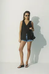 Blusa negra sin mangas con escote en V y abertura en el centro.