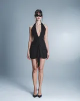 Minivestido negro con escote halter pronunciado, espalda descubierta, falda drapeada y lazo decorativo en el frente.
