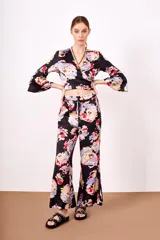 Conjunto de pantalón y top de viscosa con estampado floral en tonos rosa, celeste, amarillo y rojo sobre fondo negro. El top es cruzado con mangas acampanadas y el pantalón es de corte palazzo con cintura elastizada.