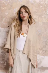 Saco/poncho tejido en algodón color beige, de silueta oversize y mangas 3/4 caídas.