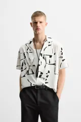 Camisa blanca con estampado abstracto en negro, de cuello bowling y manga corta.