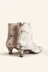 Bota corta de cuero vacuno con estampado animal print serpiente en tonos blanco y negro, con puntera fina y cierre trasero. Tiene taco chupete y suela de cuero.