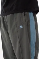 Pantalón de jogging gris con forro interno de red, bolsillos laterales con cierre, cierres en los tobillos y logo bordado.