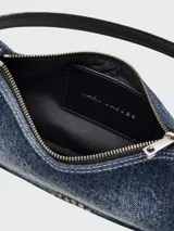 Bolso de hombro Marc Jacobs modelo The Shoulder Bag Charm, confeccionado en denim cepillado azul. Presenta una correa de cadena plateada con dijes colgantes, incluyendo una estrella y un alfiler de gancho. El bolso tiene forma curva y un cierre superior.