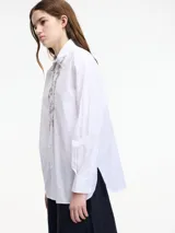 Camisa blanca de algodón con cuello camisero, cierre frontal con botones y apliques de pedrería en cuello y cartera de botones.