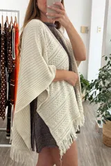 Ruana tejida color arena, con diseño calado de rombos y flecos en el borde inferior.