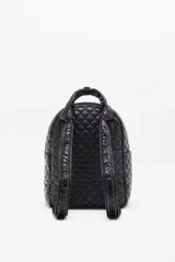 Mochila negra matelassé con correa ajustable y manijas para llevar al hombro. Tiene cierre de cremallera, accesorio colgante decorativo, bolsillo interno y espacio para laptop.