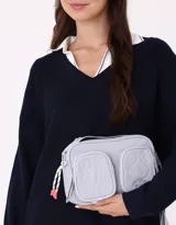 Bandolera celeste de tela deportiva acolchada con doble bolsillo con cierre, correa regulable y desmontable, manija superior, cierre superior y tag de metal.