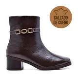 Bota corta de cuero color marrón, con taco bajo y punta cuadrada. Presenta una correa con hebilla dorada alrededor del tobillo.