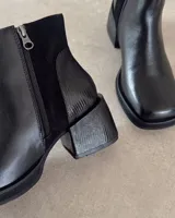 Botines negros de cuero vacuno, con paneles laterales de gamuza y tacón geométrico.