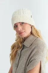 Gorro de lana color crudo, tejido en punto trenzado con detalle de etiqueta con logo en el lateral.